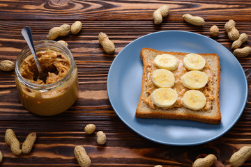 Peanut butter toast with banana slices  on wooden background