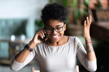 Happy African American woman excited about receiving good news by phone conversation, smiling...
