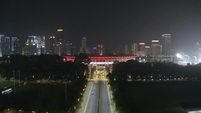 JAKARTA, Indonesia - December 12, 2018: Aerial landscape Senayan stadium with skyscrapers background at night. Shot in 4k resolution