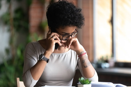 Upset African American woman talking on phone, frustrated sad female touching face, get unpleasant call, worried about problem with work or relationships, hearing, receiving bad news concept