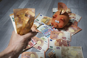 Ganar mucho dinero. Mano mostrando un fajo de billetes. Hucha cerdito llena de dinero.
