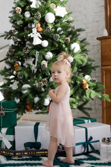 Christmas mood. Little girl staying near Christmas tree