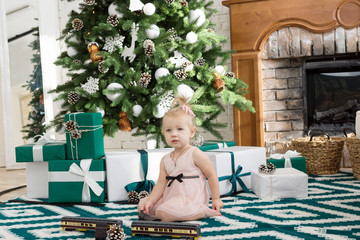 Little girl sitting near Christmas tree