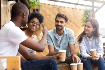 African American man showing thumb up, telling story to interested attentive friends, sitting, drinking coffee in cafe together, smiling multiethnic friends discussing, talking, chatting - obrazy, fototapety, plakaty