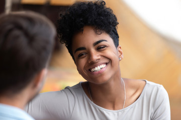 Smiling happy African American woman looking at man, black excited girlfriend having conversation with boyfriend, acquaintance, compliment, first impression, good date concept, close up