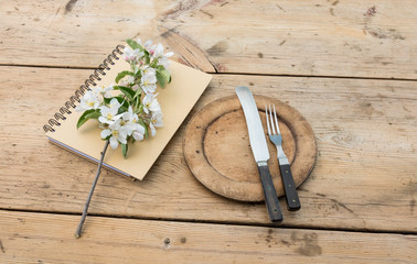An old table with a notebook, plate and cutlery