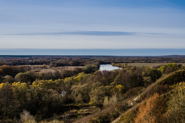 The river flows through the forest in the plain overlooking the hill