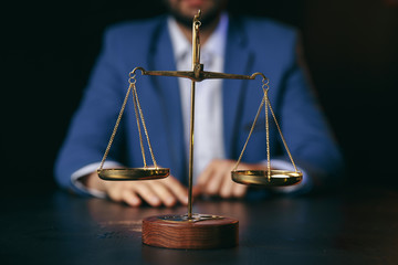 justice and law concept.Male lawyer in the office with brass scale on wooden table,reflected view