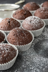 Fresh muffins with sugar icing on a wooden black table.