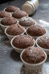 Fresh muffins with sugar icing on a wooden black table.