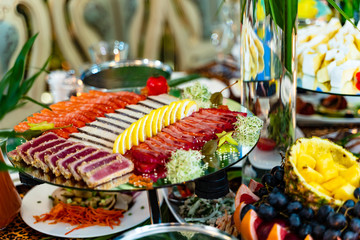Different kinds of meat sliced with lemon in a plate on a festive table. Nicely decorated plate with meat and lemon on a special plate. Close-up