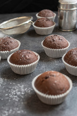 Fresh muffins with sugar icing on a wooden black table.