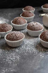 Fresh muffins with sugar icing on a wooden black table.
