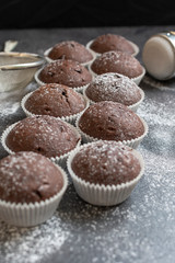 Fresh muffins with sugar icing on a wooden black table.