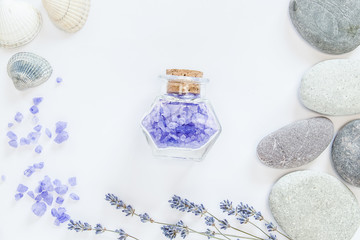 Fototapeta na wymiar Flowers of lavender, decorative bottles, sea salts, seastones and seashells on the white background.