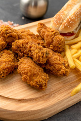 Hamburger and chicken strips on a wooden table. Fast food concept. 