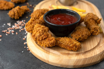 Chicken strips, french fries, and ketchup on a wooden tray. Fast food concept. 