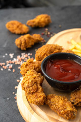 Chicken strips, french fries, and ketchup on a wooden tray. Fast food concept. 