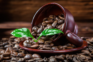 coffe beans scattered from cup and leaves.