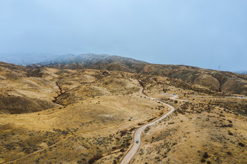 A SUV drives towards rugged mountains on an overcast day in Boise, Idaho.