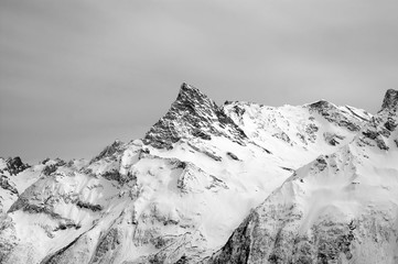 Black and white snowy mountains and grey cloudy sky