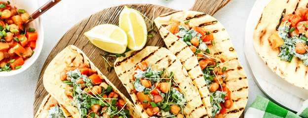 vegetarian snack of tacos with chickpea curry and sour cream sauce with parsley, spinach, green onions and sprouted flax seeds. healthy plant based food. top view on light background, banner