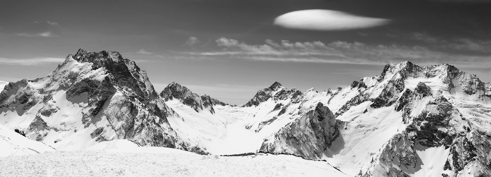 Black and white panorama of snowy mountains and sky with clouds