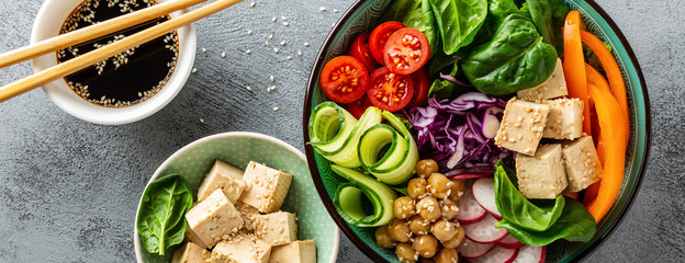 Buddha bowl salad with chickpeas, sweet pepper, tomato, cucumber, red cabbage kale, fresh radish, spinach leaves and tofu cheese, healthy balanced clean eating concept, top view, banner