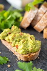 Fresh bread with Mexican homemade guacamole on a black table.
