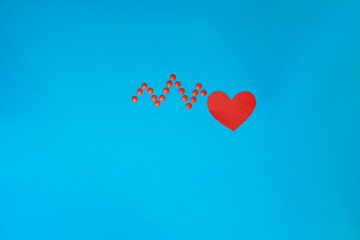 The shape of a red heart and a zigzag of pills in the form cardiogram on a blue background