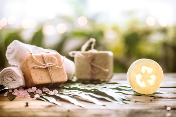 Fototapeta na wymiar Spa handmade soap and a towel, the composition of the tropical leaves wooden background