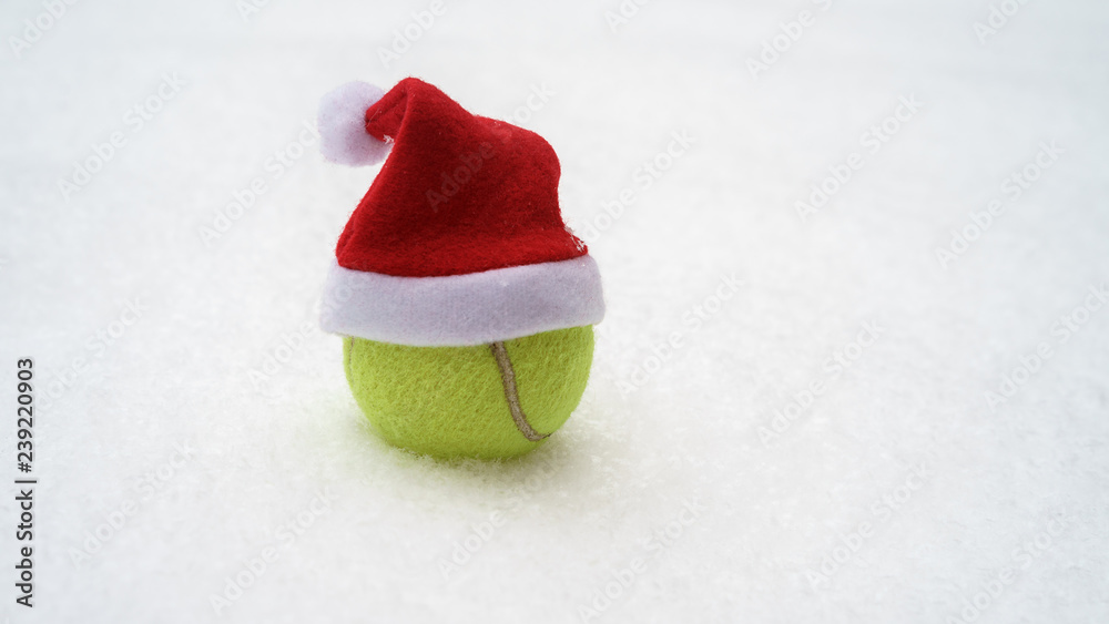 Wall mural Santa hat on tennis ball on white snow winter background. Merry Christmas and New year concept with tennis balls. Close up, sport lifestyle, funny. Isolated