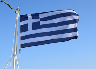 The national flag of Greece is developing in the wind on the flagpole. Greek flag on the mast aft...