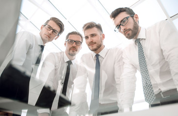 bottom view.serious business team standing together and looking at the camera