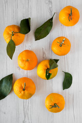 Fresh ripe unshelled tangerines on a white wooden background, top view. Flat lay, from above, overhead. Closeup.