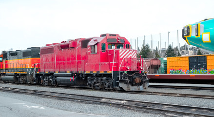 A red train sits on the tracks in a rail yard 
