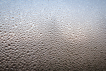 The frozen drops on the patterned frosty winter window