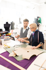 High angle portrait of two fashion designers working on clothes while standing at table in atelier workshop, copy space