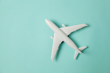 Simply flat lay design miniature toy model plane on blue pastel colorful paper trendy background. Travel by plane vacation summer weekend sea adventure trip journey ticket tour concept