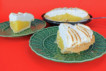 Lemon Meringue Pie being Sliced and Served on Green Plates on Red BG
