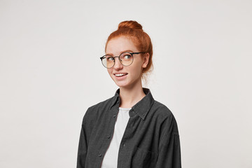 Headshot of an attractive charming female with red hair, dreamily looks away, imagine something pleasant, nicely smiling, over white studio background