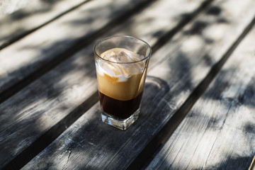 An ice coffee with ice cubes and milk on a wooden table