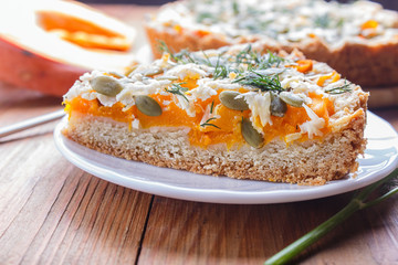 a piece of sweet pumpkin pie with cheese and dill on brown wooden background.
