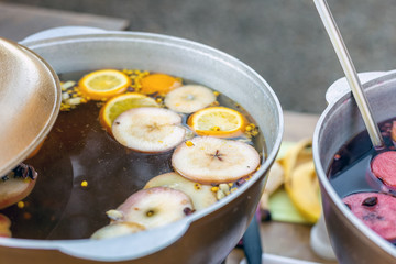 Mulled wine prepared in iron pot at city street fair. Traditional christmas and new year alcohol drink - hot wine. Stall with drinks in town at winter holiday fest