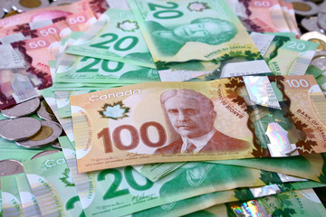 Many canadian dollar bills and spare change spread and filling the frame.