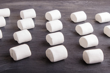 Fototapeta na wymiar set of marshmallows on black wooden background. geometric pattern.