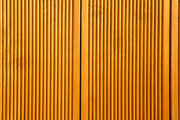 Yellow wooden wall panels decorated with vertical grooves. Abstract geometrical carved wood background