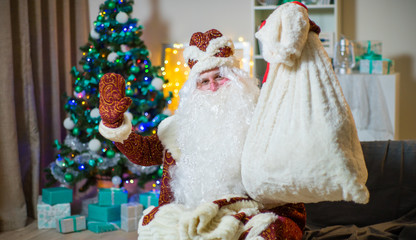 Portrait of Santa Claus in a red suit on the background of the Christmas tree.