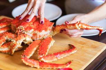 women's hands is taking leg from big red cooked crab for food © Aidman