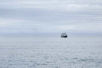 Obraz premium Fishing boat at sea on a cloudy morning. Alone into the big ocean.